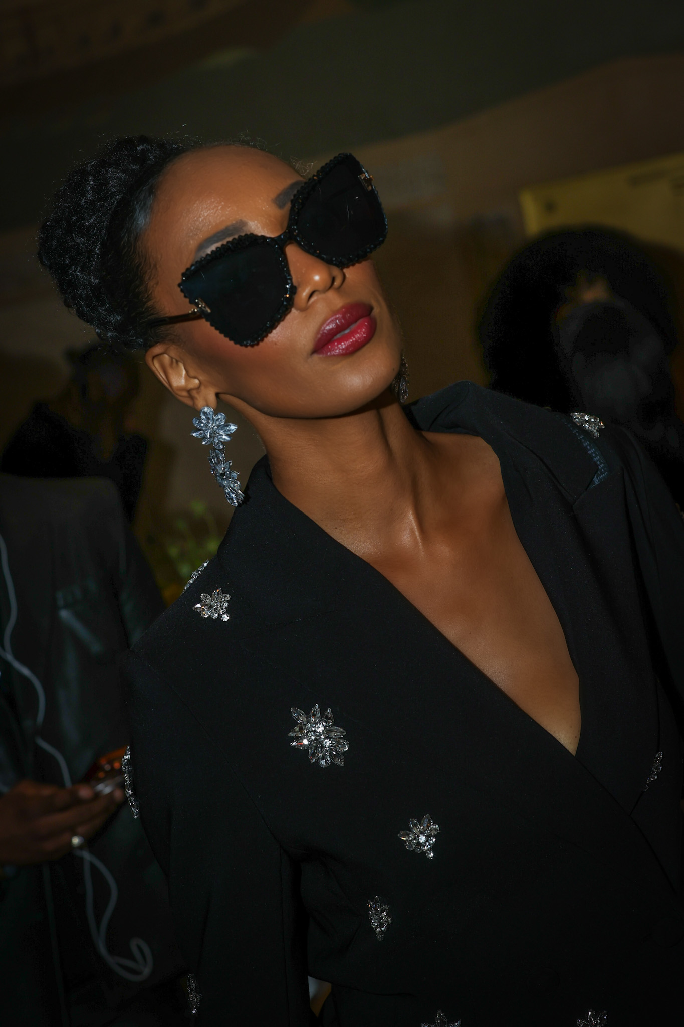 Editorial portrait in a black jacket with crystal details and beaded sunglasses
